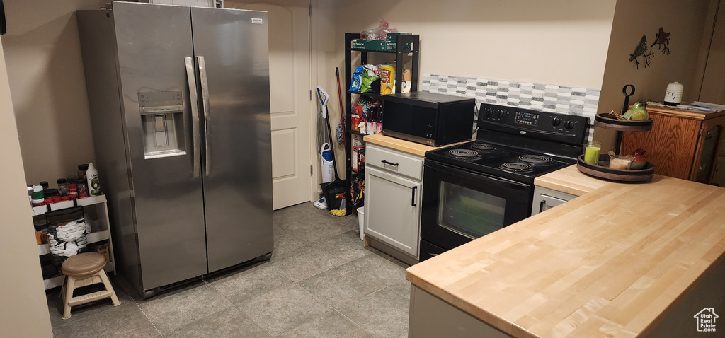 Kitchen featuring black appliances, wood counters, white cabinetry, and decorative backsplash