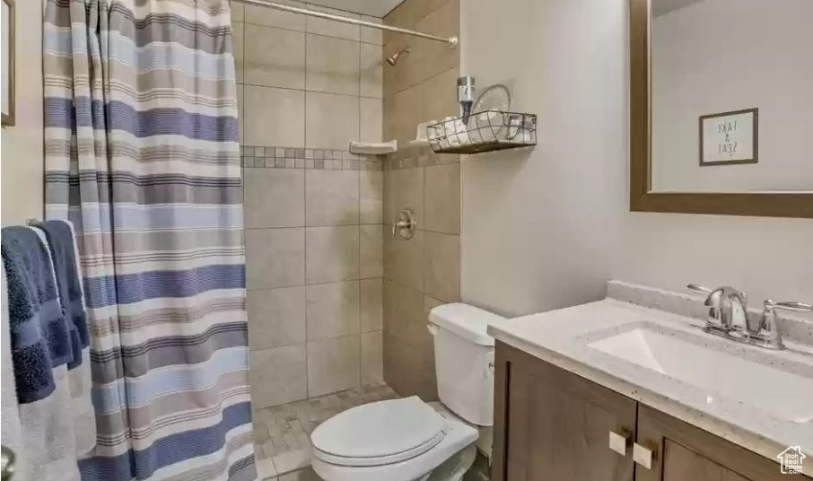 Bathroom featuring vanity, toilet, and tiled shower