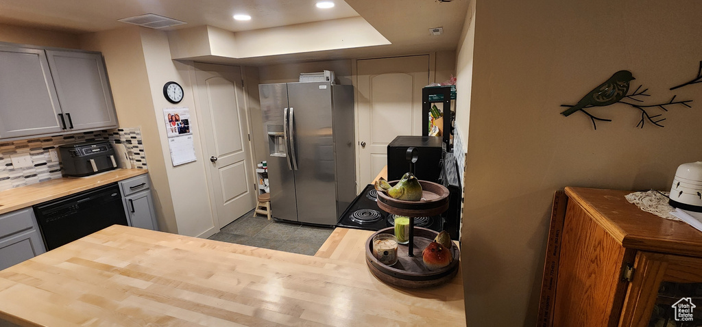 Kitchen with stainless steel refrigerator with ice dispenser, black dishwasher, gray cabinetry, butcher block countertops, and recessed lighting