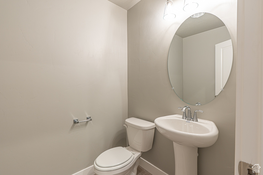 Half bathroom with toilet and baseboards
