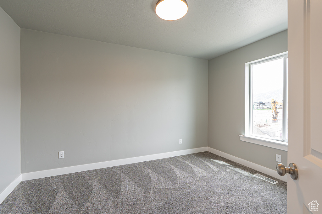 Carpeted empty room featuring baseboards