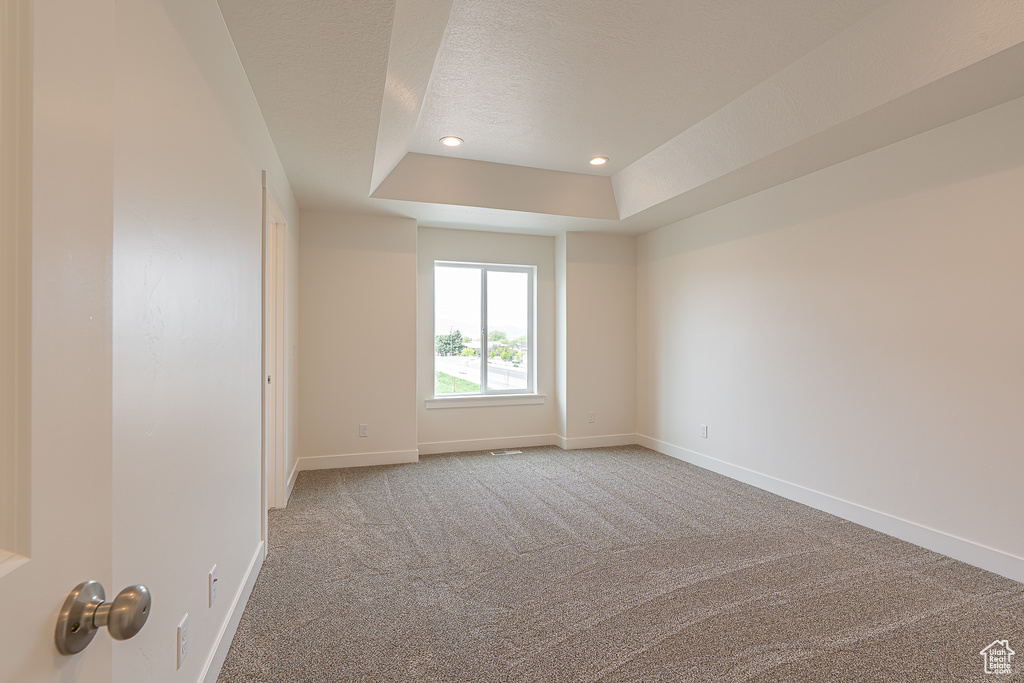 Empty room with a raised ceiling, carpet flooring, a textured ceiling, and recessed lighting
