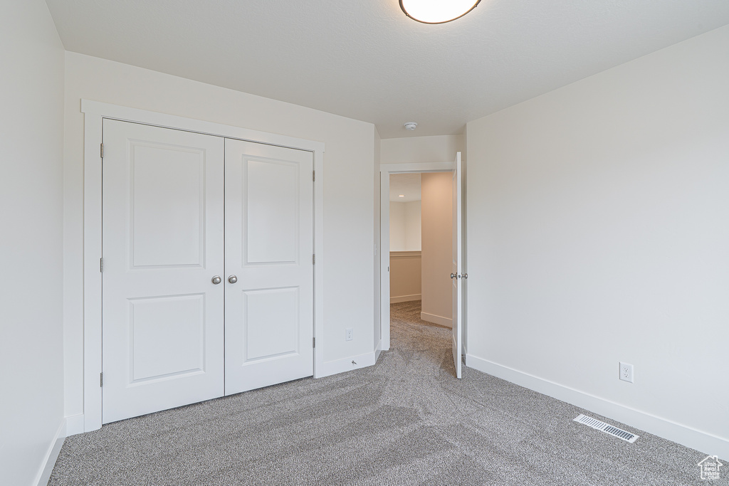 Unfurnished bedroom featuring carpet and a closet