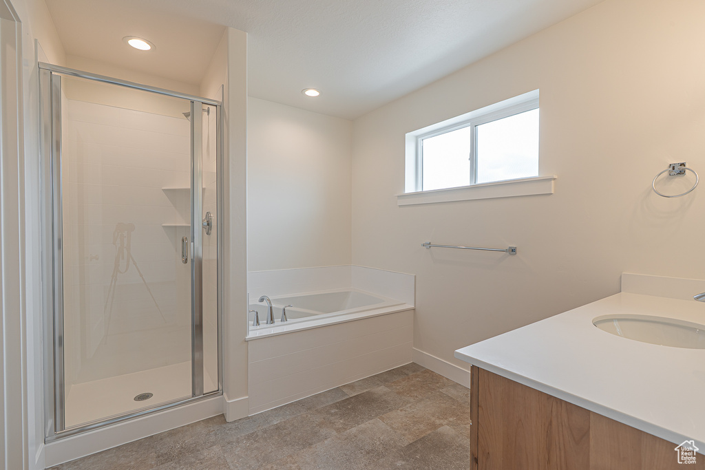 Full bathroom featuring a garden tub, vanity, a shower stall, recessed lighting, and stone finish floors