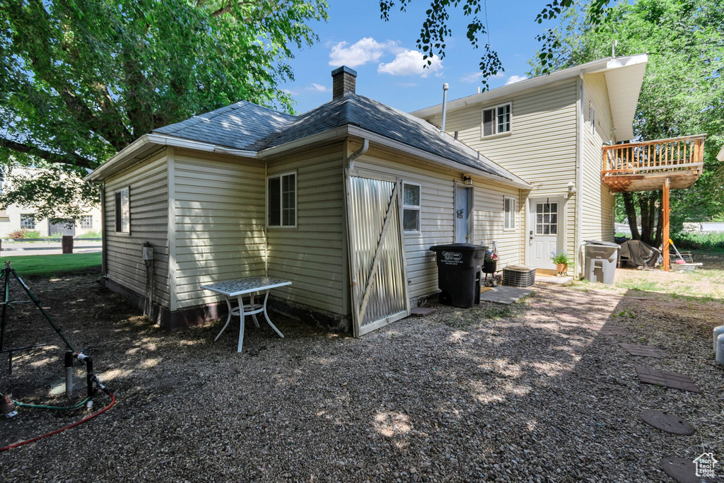 Back of property featuring a chimney and roof with shingles