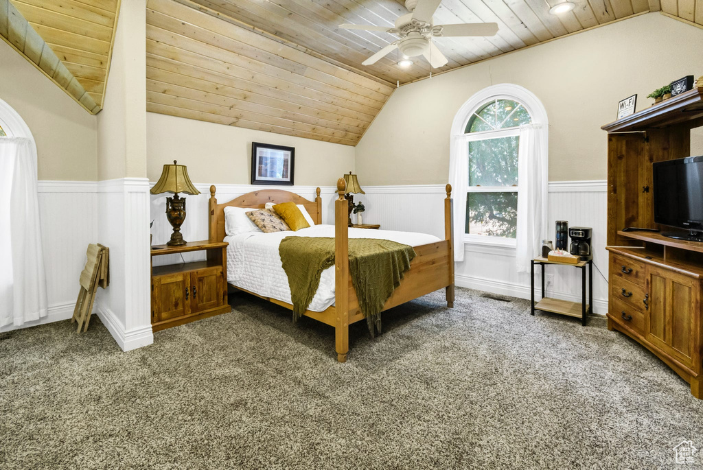 Bedroom with lofted ceiling, wooden ceiling, carpet, a wainscoted wall, and ceiling fan