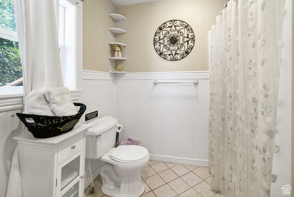 Full bath with a wainscoted wall, tile patterned flooring, and a shower with curtain