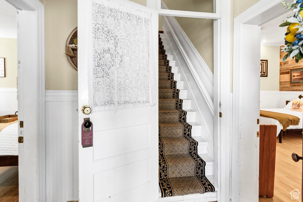 Stairs featuring wainscoting and wood finished floors