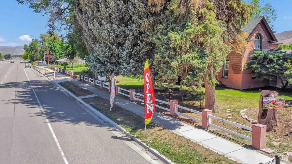 View of asphalt road featuring street lighting, sidewalks, and curbs