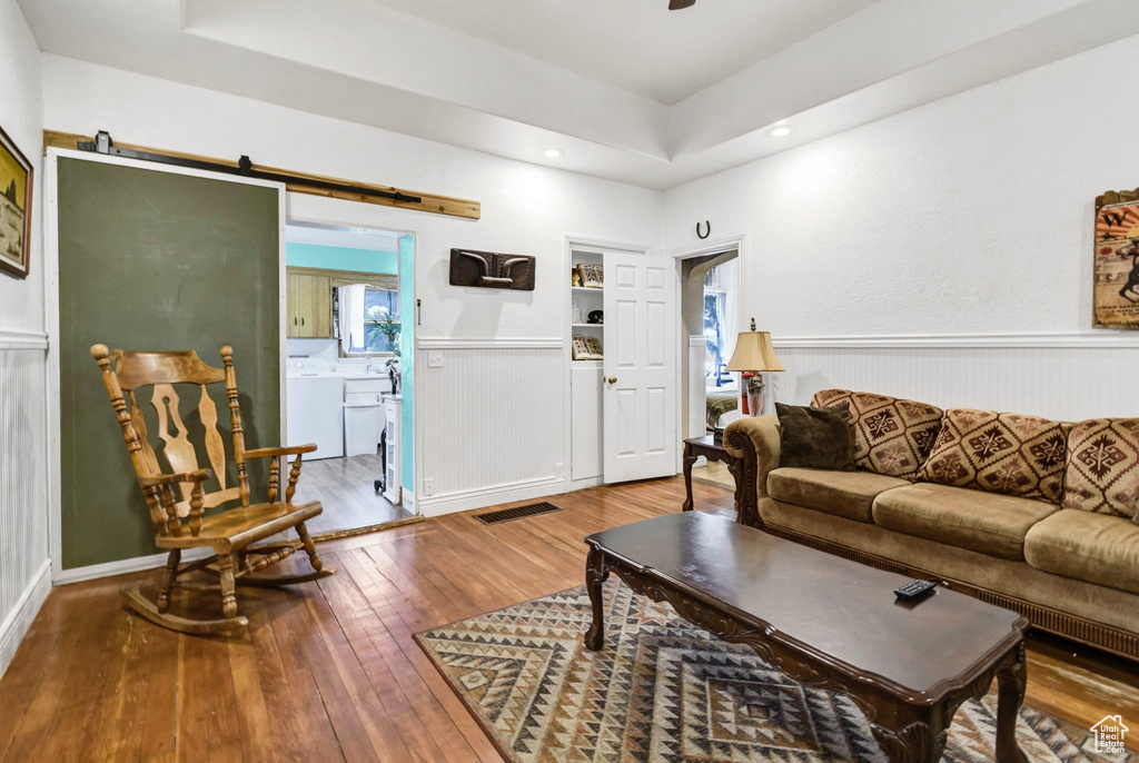 Living area featuring washer / clothes dryer, hardwood / wood-style flooring, a tray ceiling, wainscoting, and recessed lighting