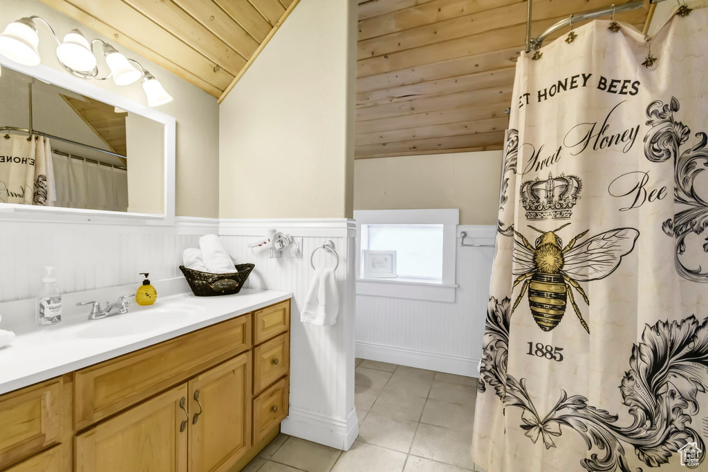 Bathroom with wood ceiling, vanity, lofted ceiling, wainscoting, and tile patterned floors