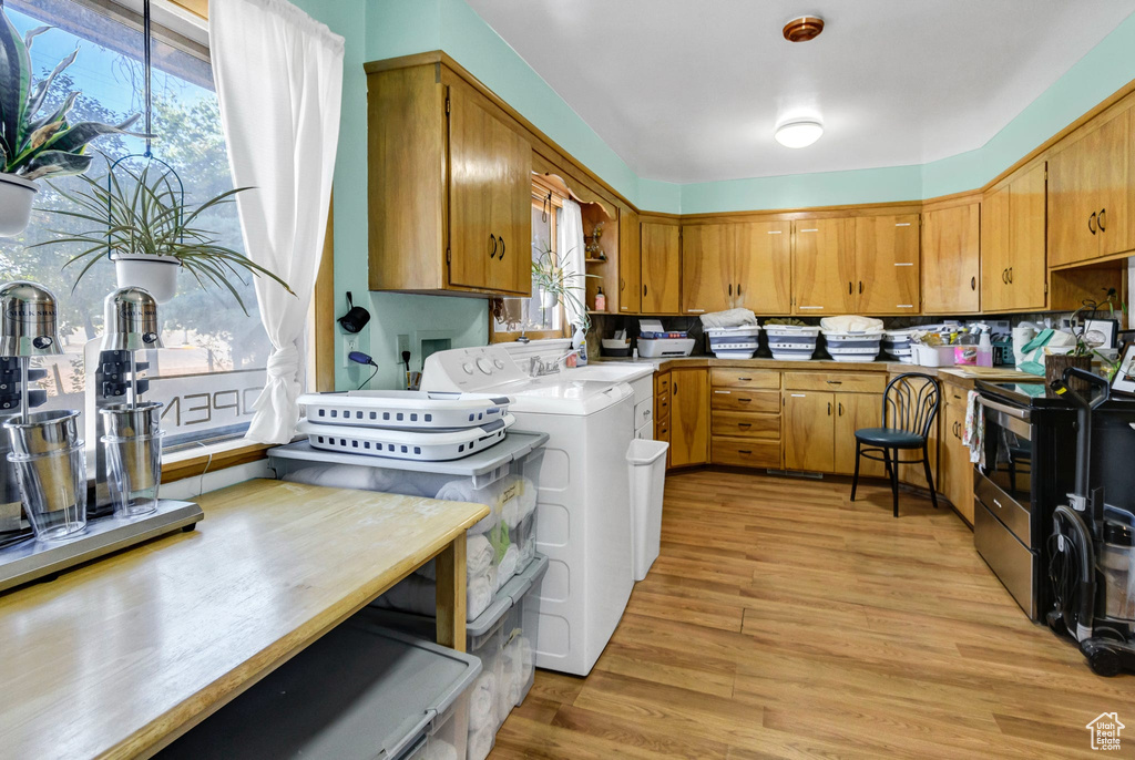 Kitchen with electric stove, separate washer and dryer, brown cabinetry, and light wood finished floors