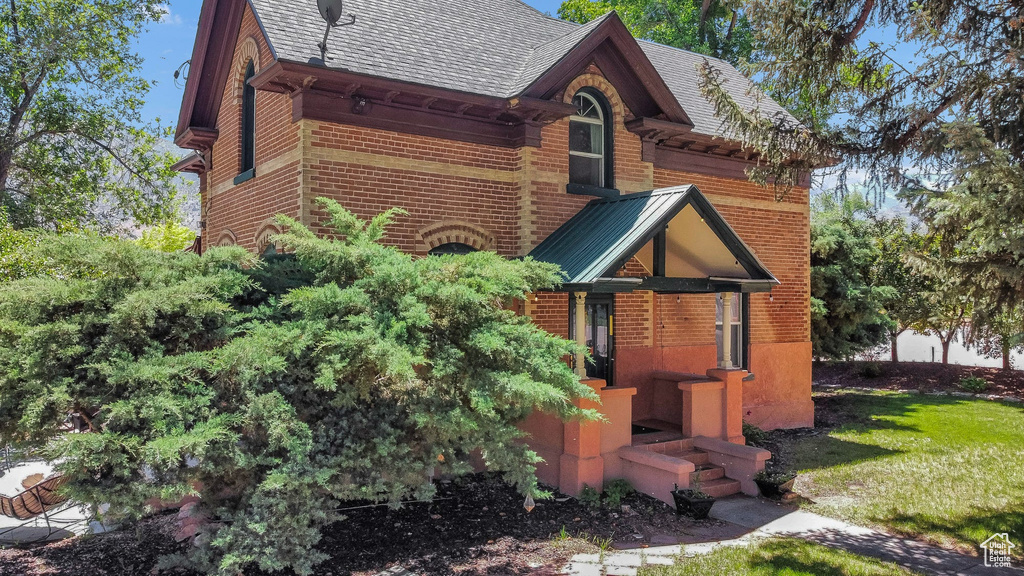 View of front of house with brick siding, a front lawn, and roof with shingles