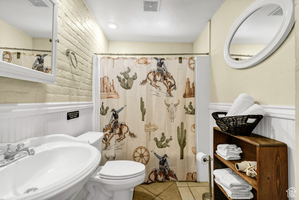 Full bath featuring tile patterned floors, wainscoting, and curtained shower