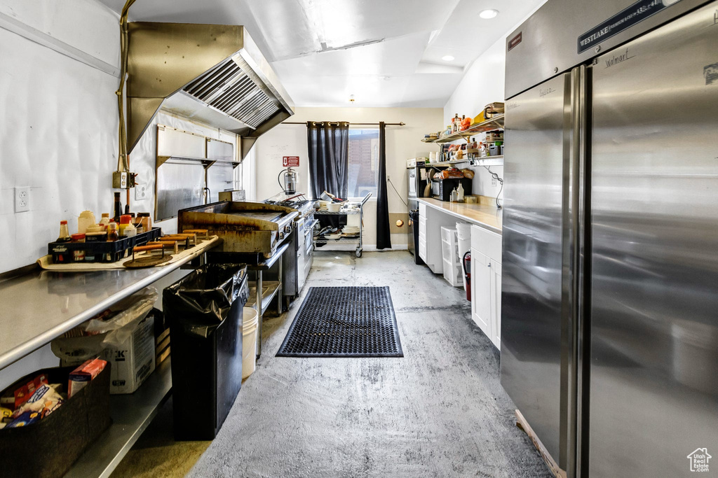 Kitchen with high end refrigerator, white cabinets, concrete flooring, open shelves, and recessed lighting