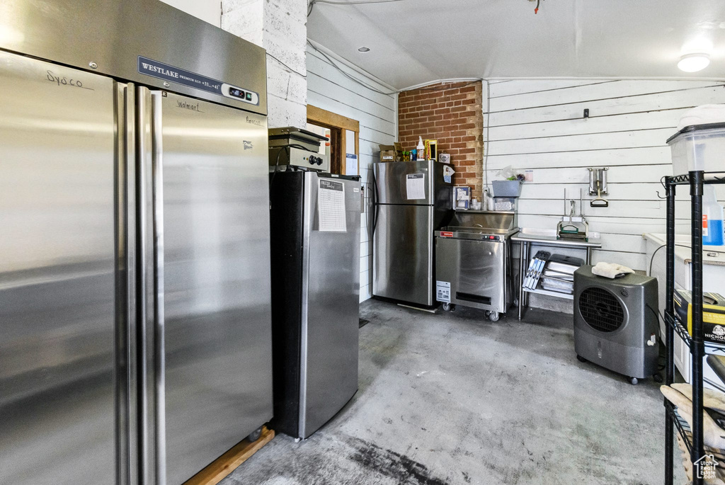 Kitchen featuring high end refrigerator, freestanding refrigerator, concrete floors, washer / dryer, and lofted ceiling