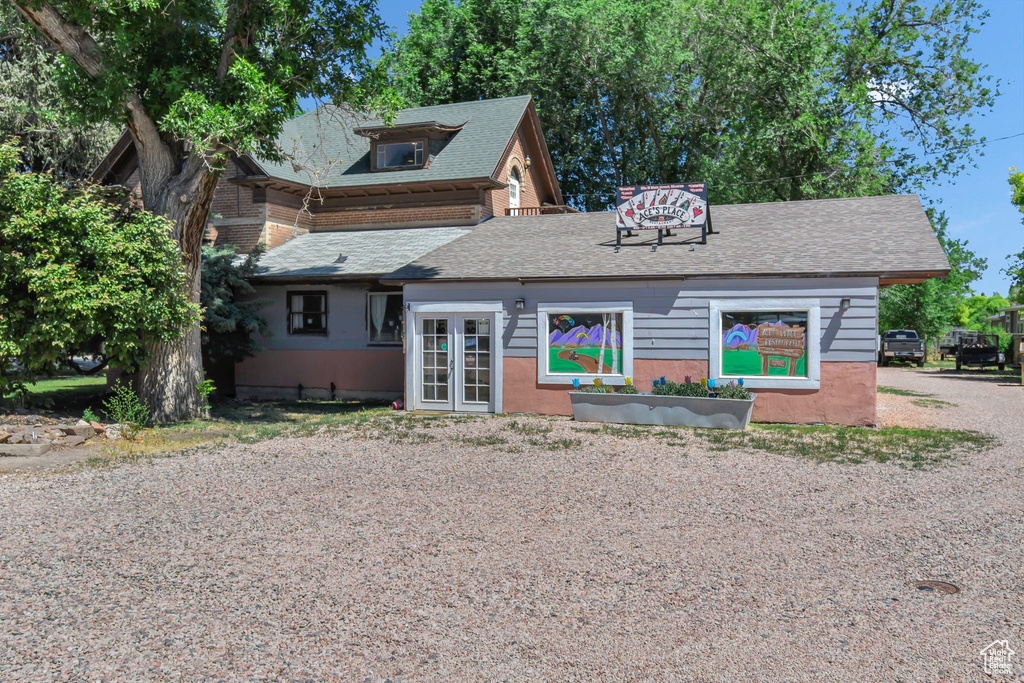 View of front of property featuring french doors and roof with shingles