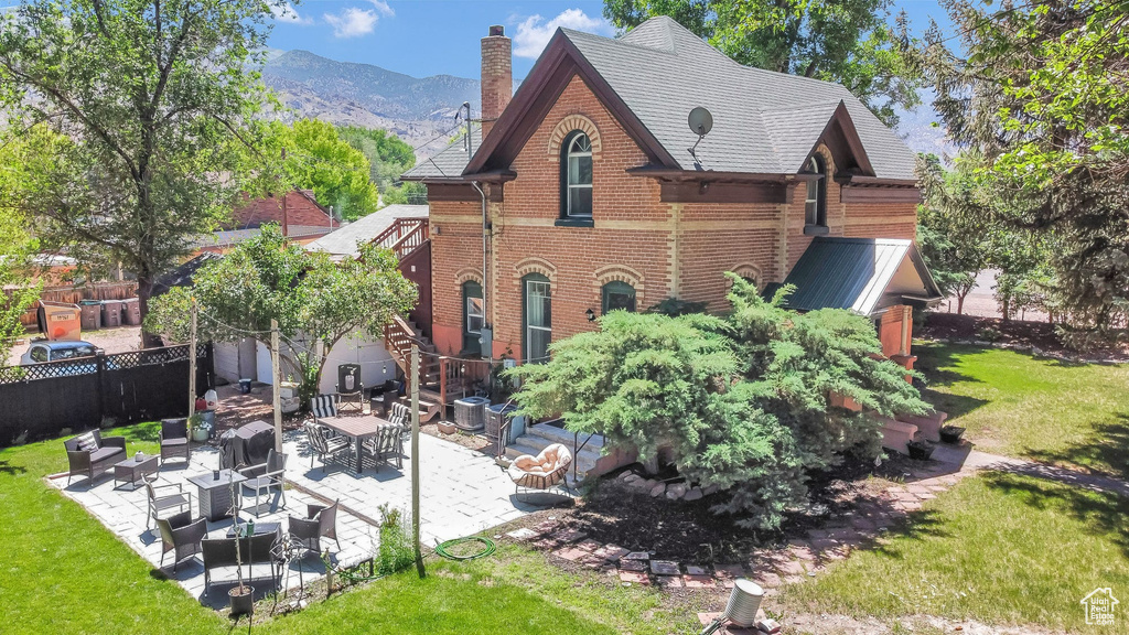 Rear view of house featuring brick siding, an outdoor living space, a patio area, a chimney, and a mountain view