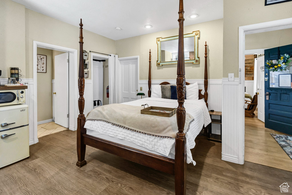 Bedroom with wainscoting, wood finished floors, and a decorative wall