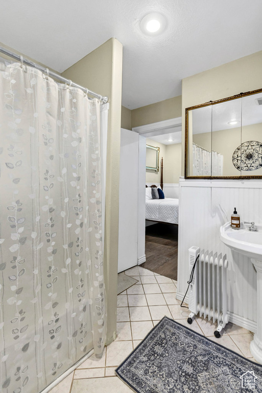 Bathroom featuring ensuite bathroom, tile patterned flooring, radiator, wainscoting, and curtained shower