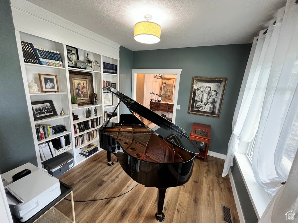 Living area with wood finished floors, a textured ceiling, and built in features