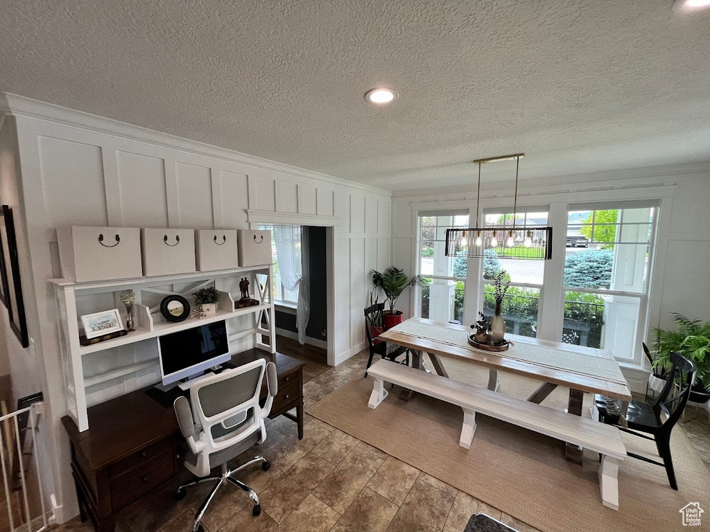 Dining room with a decorative wall, a textured ceiling, and a desk