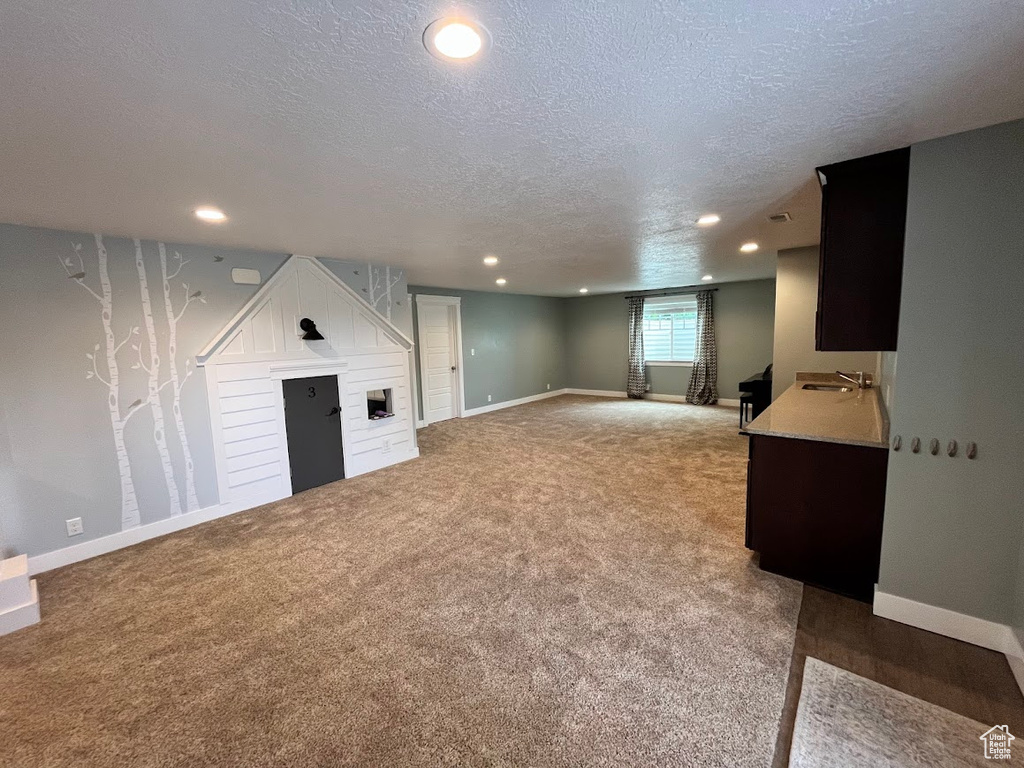 Below grade area featuring a textured ceiling, light carpet, recessed lighting, and a fireplace