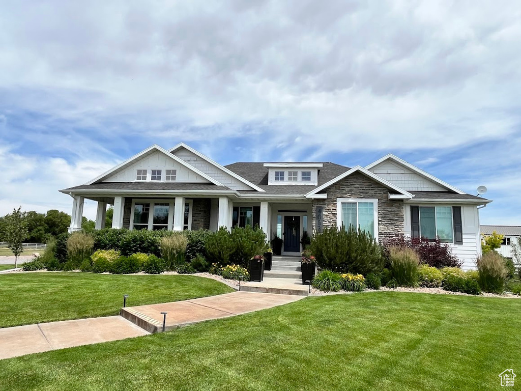 Craftsman house with a front lawn, stone siding, and roof with shingles