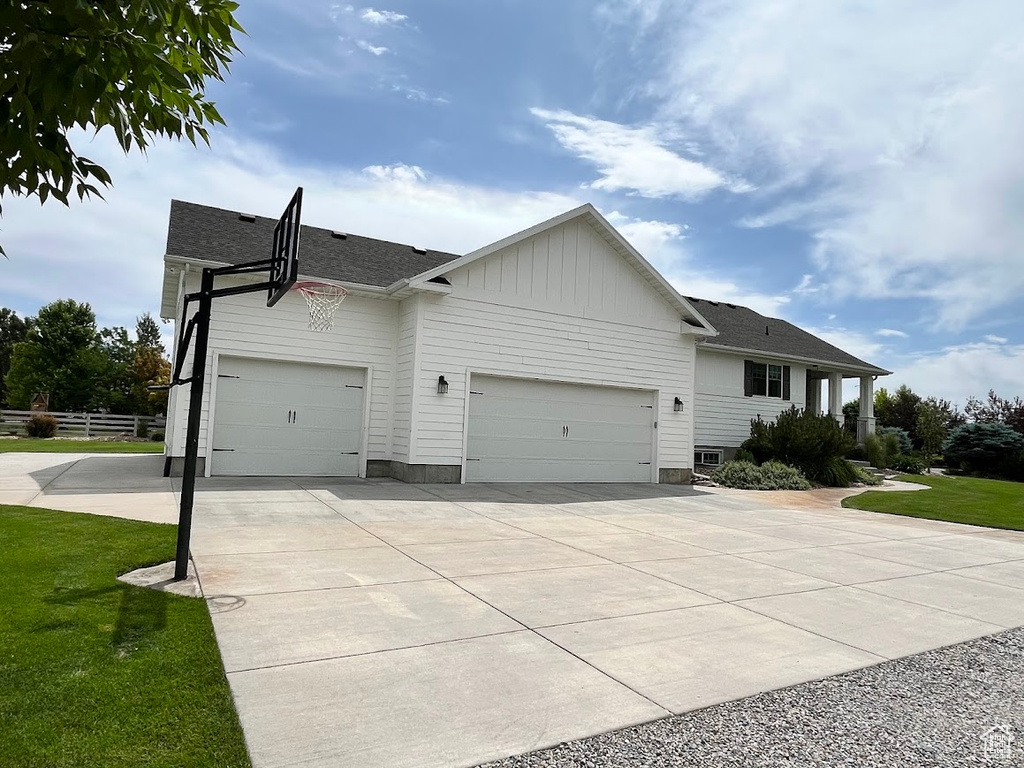 View of front facade with an attached garage, driveway, a shingled roof, and board and batten siding