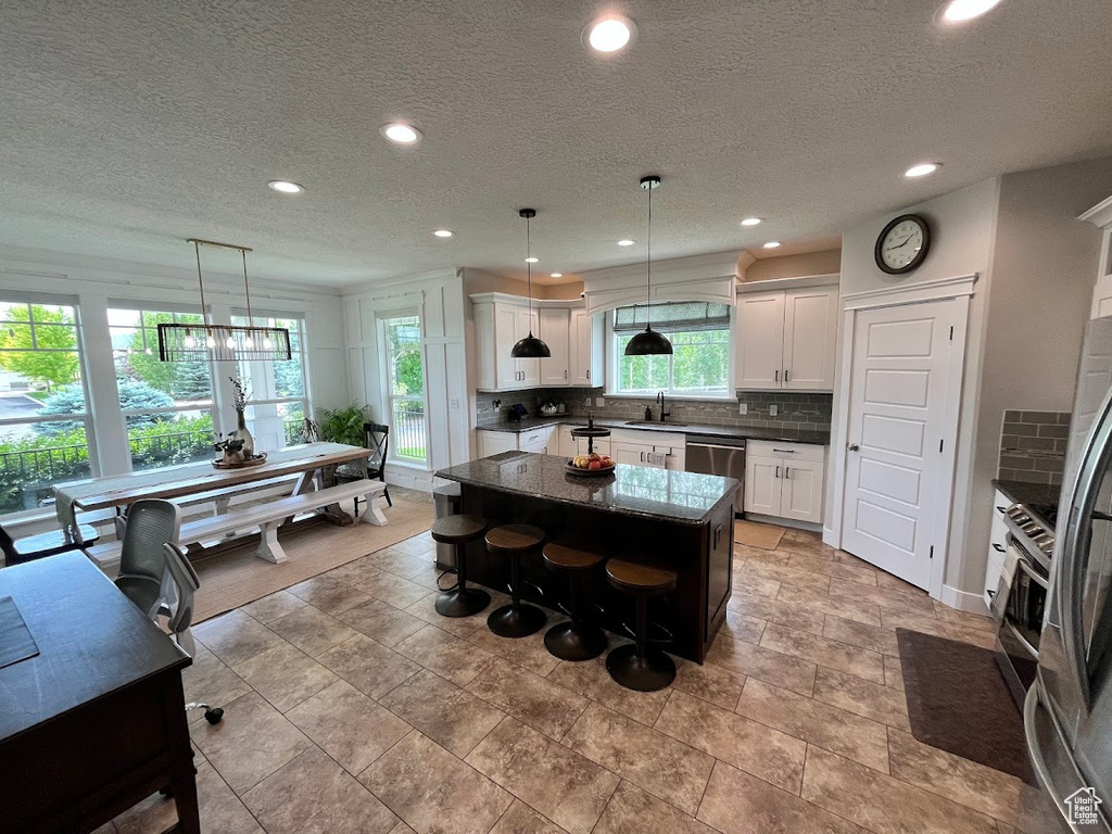 Kitchen with appliances with stainless steel finishes, a center island, decorative backsplash, recessed lighting, and white cabinets