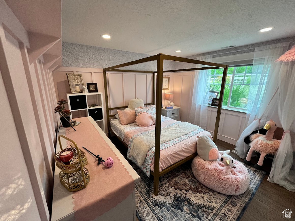Bedroom with a decorative wall, wood finished floors, and recessed lighting