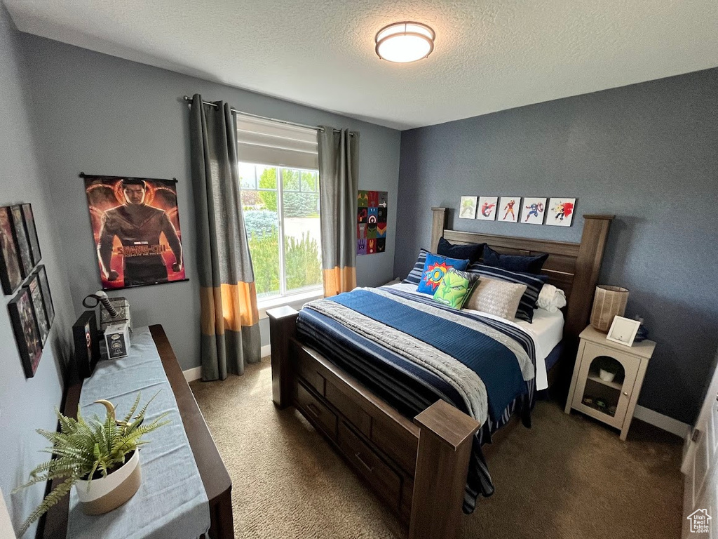 Carpeted bedroom featuring a textured ceiling and baseboards