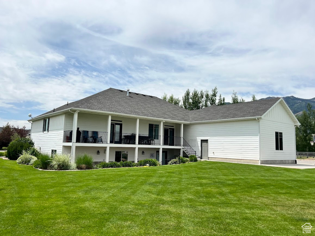 Back of house featuring a lawn and roof with shingles