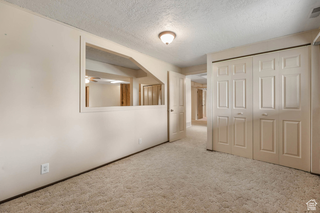 Unfurnished bedroom with carpet flooring, a textured ceiling, and a closet