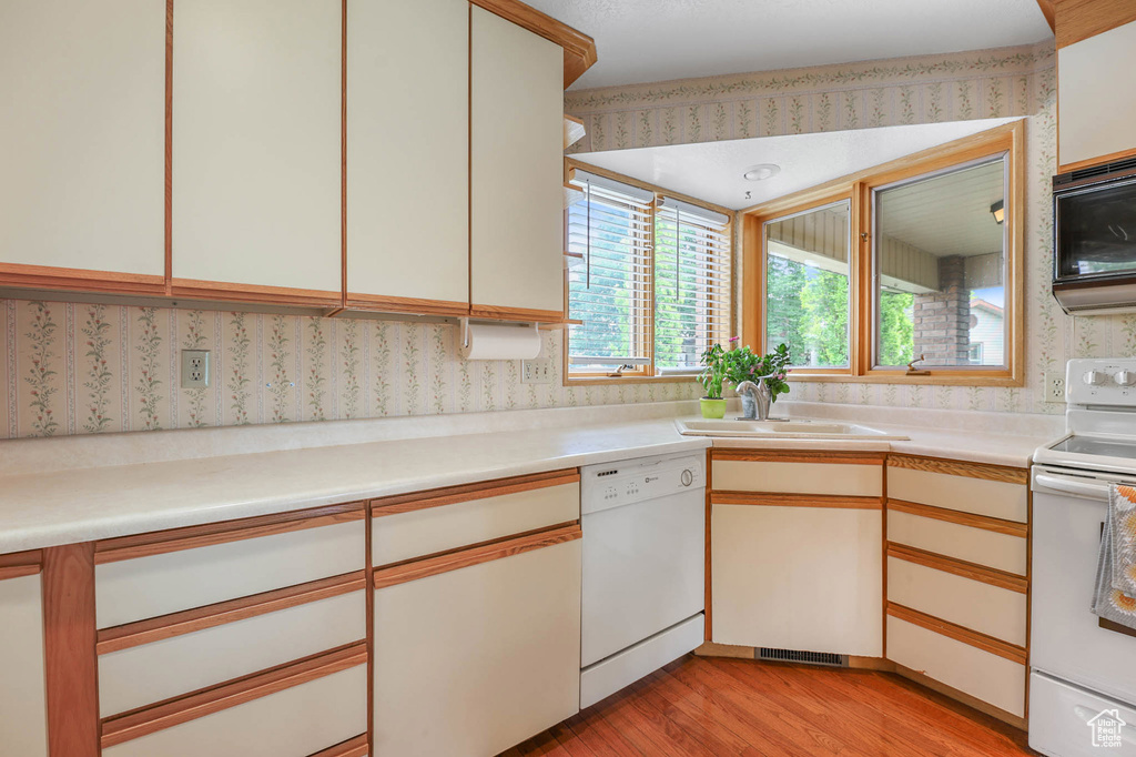 Kitchen with white appliances, light wood finished floors, and light countertops