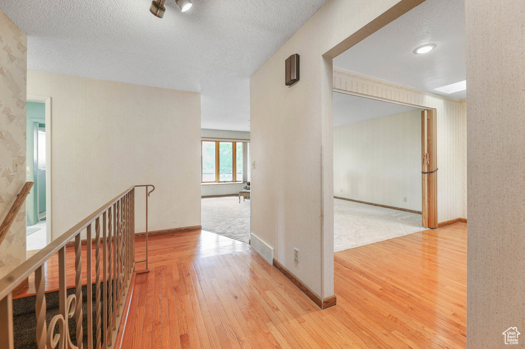 Hall with light wood-style floors and a textured ceiling