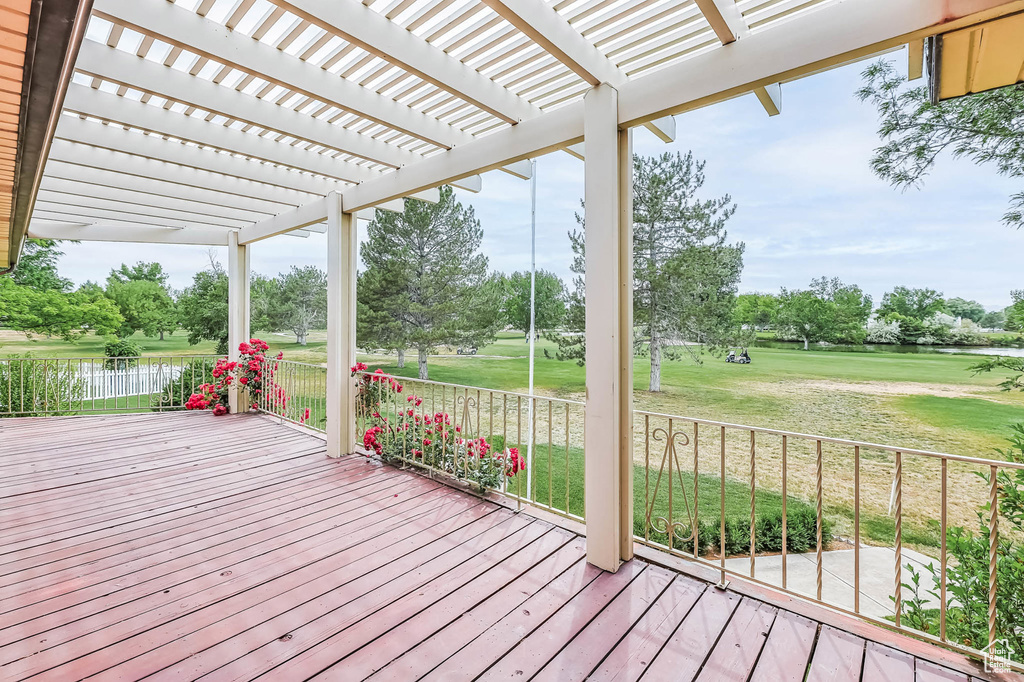 Deck with a pergola, a water view, a yard, and view of scattered trees