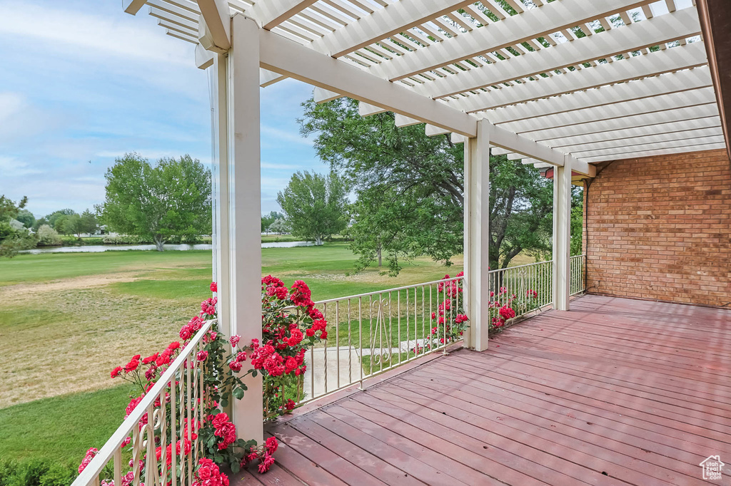 Porch with a pergola, a water view, a lawn, and golf course view