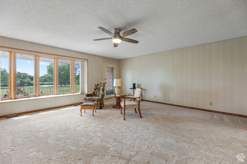 Sitting room featuring ceiling fan, a textured ceiling, and carpet flooring