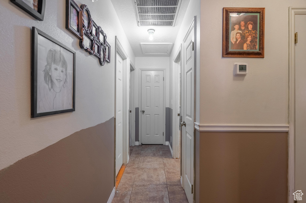 Corridor featuring tile patterned flooring and attic access