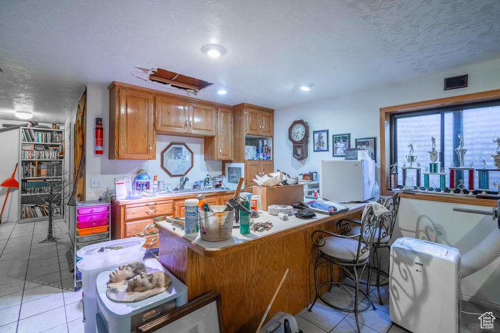 Kitchen with light tile patterned floors, light countertops, a breakfast bar, a desk, and recessed lighting