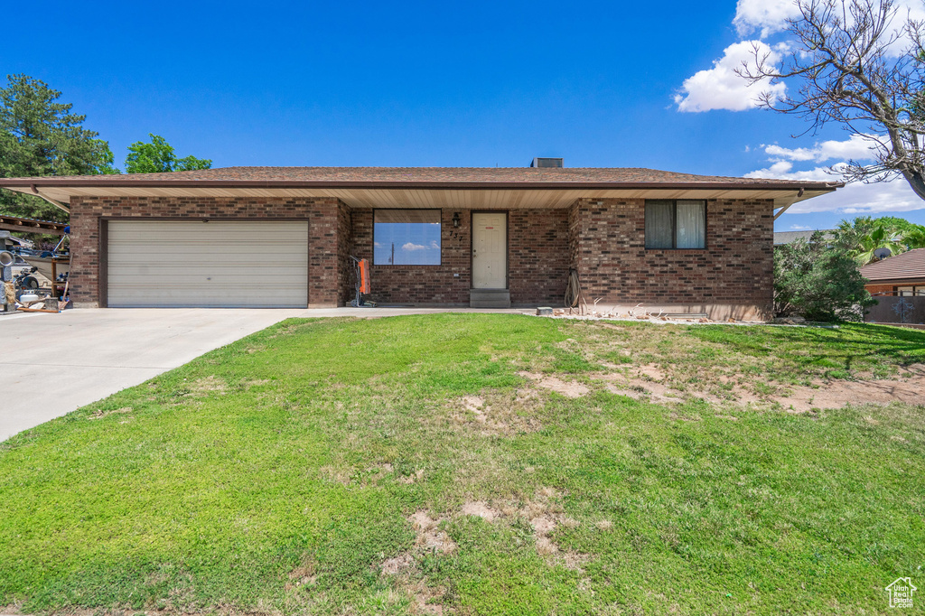 Ranch-style house with brick siding, a garage, concrete driveway, and a front lawn