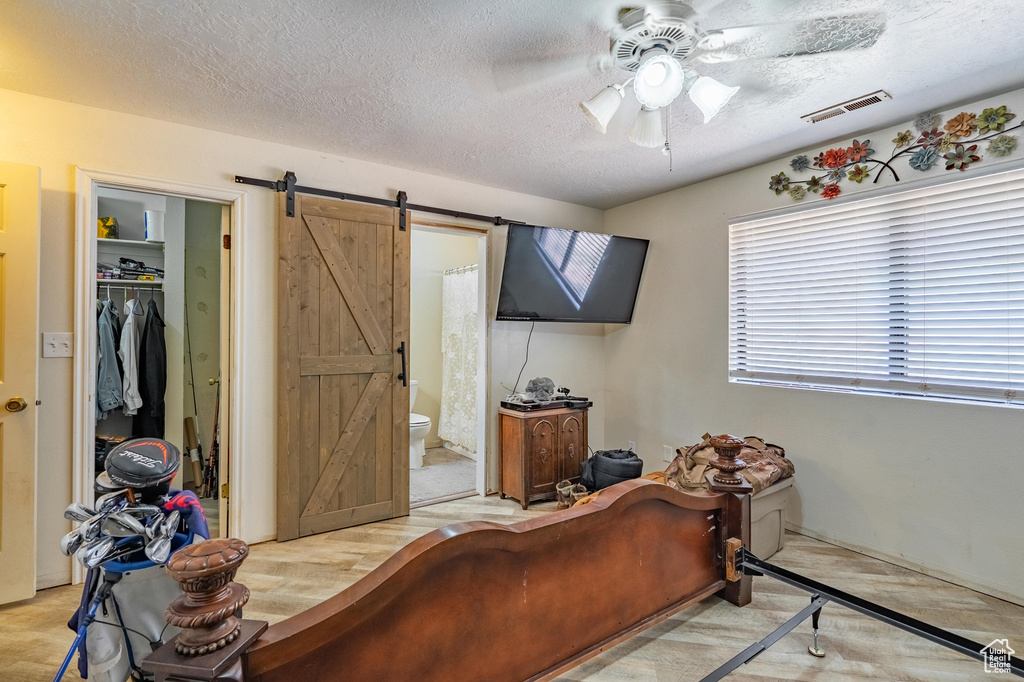 Bedroom with a barn door, a textured ceiling, a walk in closet, ensuite bathroom, and a closet