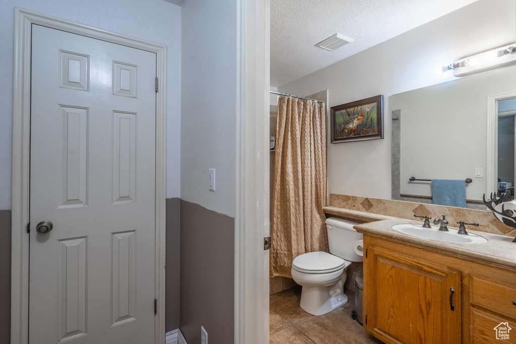 Full bathroom featuring tile patterned flooring, vanity, a shower with shower curtain, and a textured ceiling