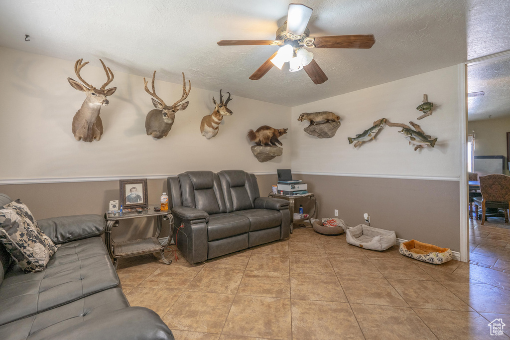Tiled living area featuring ceiling fan and a textured ceiling