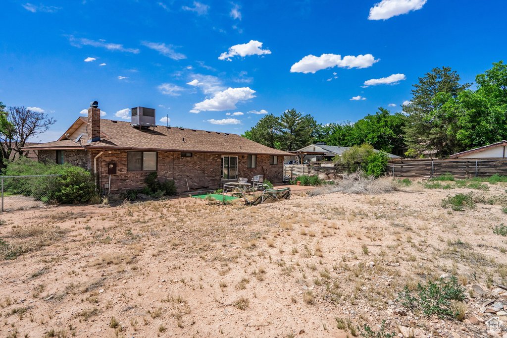 Rear view of house featuring a chimney, a fenced backyard, and brick siding
