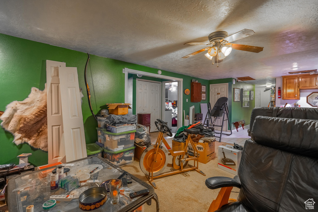 Carpeted living area with a textured ceiling and a ceiling fan