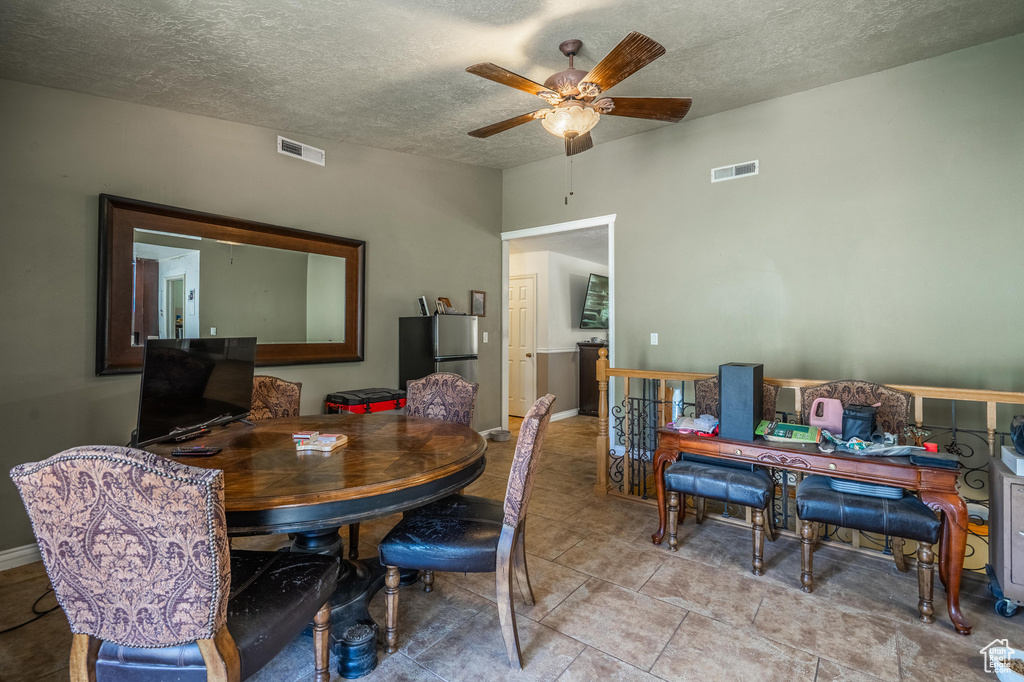 Dining room featuring ceiling fan, a textured ceiling, light tile patterned flooring, and an office area