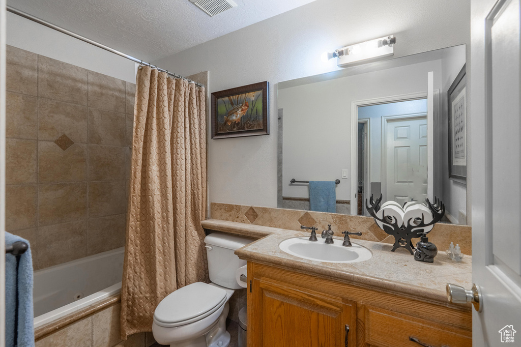Bathroom featuring vanity, tiled shower / bath combo, and a textured ceiling