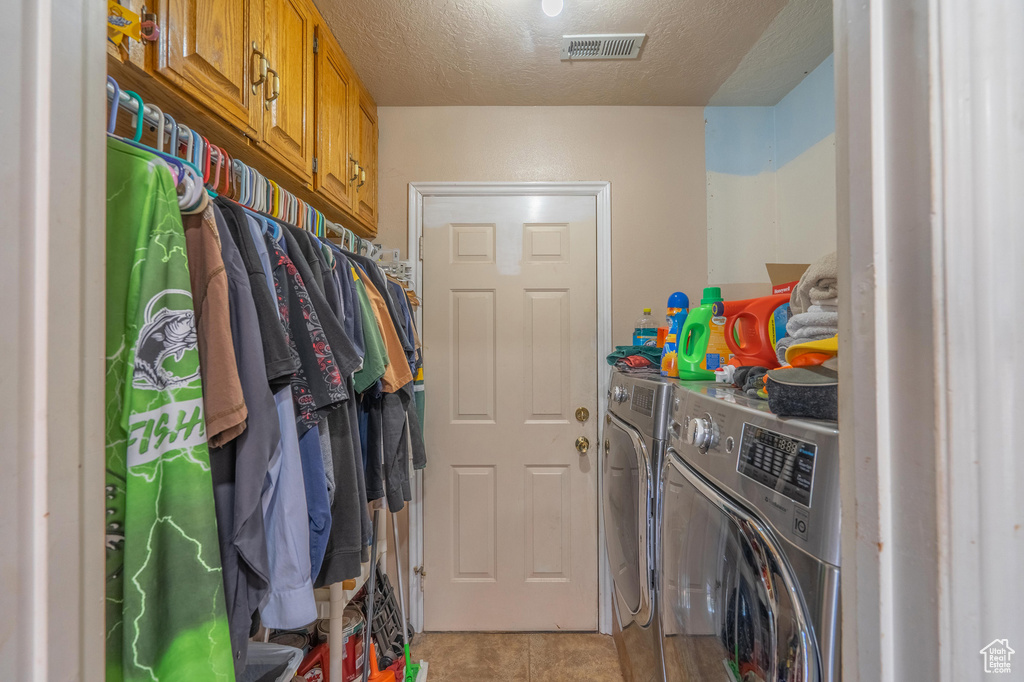 Washroom featuring independent washer and dryer, light tile patterned flooring, and a textured ceiling